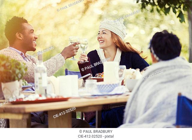 Couple toasting wine glasses at patio lunch table