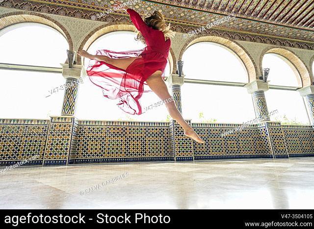 Young woman jumping a large grand jete while dancing, photographed in flight