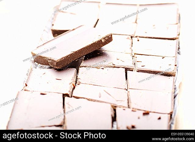 Dark chocolate bar broken into pieces laying in a foil on paper wrap