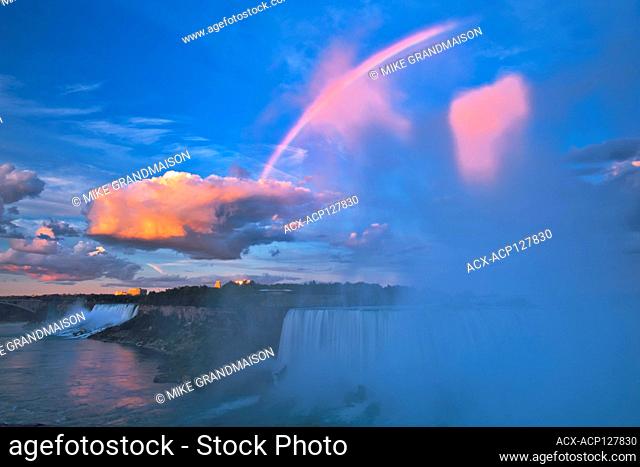 Storm clouds at sunrise with fog and rainbow as The Niagara River plunges over Niagara Falls. Golden Horseshoe. Niagara Peninsula. Ontario Canada