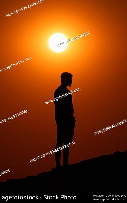SYMBOL - 09 July 2023, Serbia, Belgrad: A man stands on a wall at Kalemegdan Park at sunset. Thereby he can be seen as a silhouette