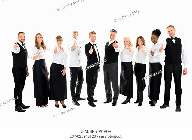 Full length portrait of confident restaurant staff standing in row against white background