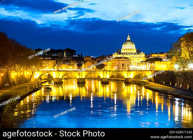 Beautifully lighted river view of Ponte Sant'Angelo and Vatican City Saint Peter's Basilica at dusk in Rome, Italy during winter