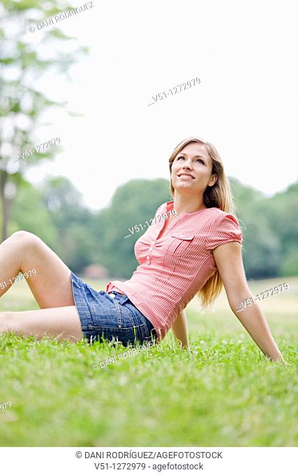 Portrait of a blonde beautiful woman sitting in the park in Spring
