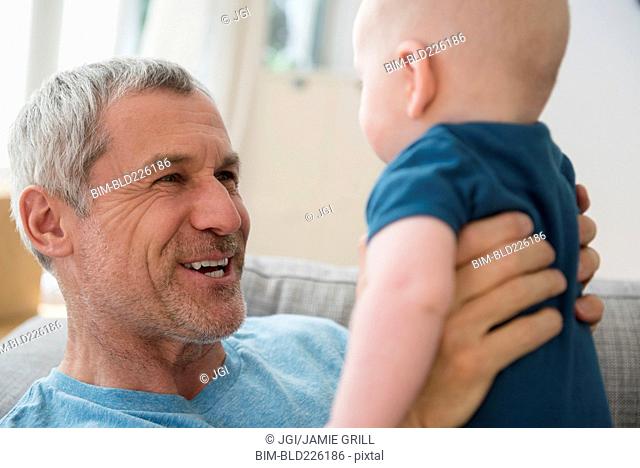 Caucasian grandfather holding grandson face to face