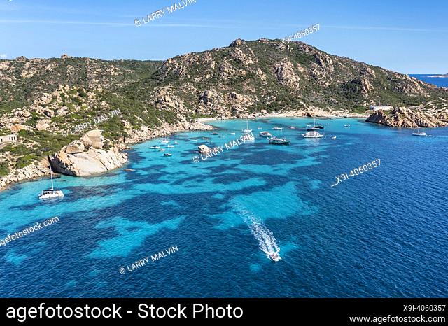 Aerial view of Spargi Island with Cala Corsara, a white sand beach bathed by a turquoise water and a tourist speedboat in the La Maddalena Archipelago