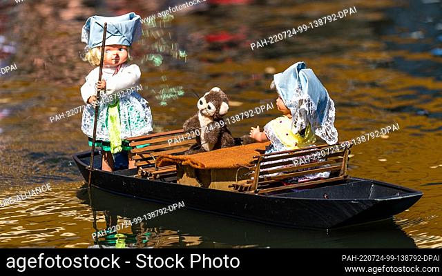 23 March 2022, Brandenburg, Lübbenau: Two dolls in traditional costumes typical of the Spree Forest and an otter figure sail on an electrically operated...