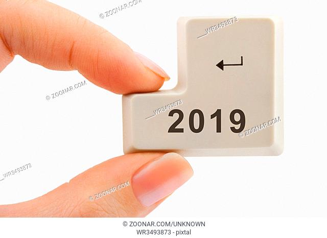 Computer button 2019 in hand isolated on white background