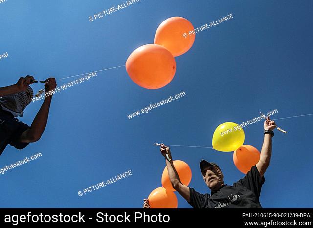 15 June 2021, Palestinian Territories, Gaza City: Masked Palestinians release refrigerant gas-filled balloons, attached to incendiary devices and flammable...