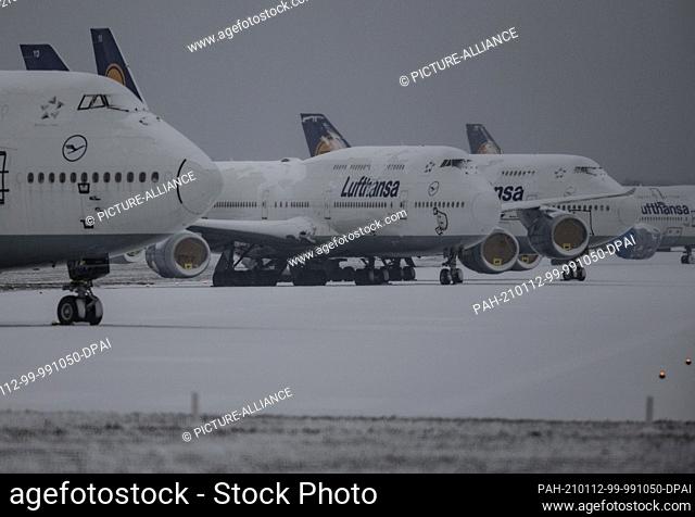 12 January 2021, Hessen, Frankfurt/Main: Snow lies on mothballed Lufthansa passenger planes parked on the disused northwest runway at Frankfurt Airport