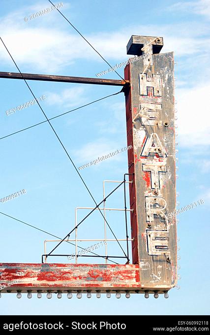 Vertical composition metal neon theatre sign against blue sky