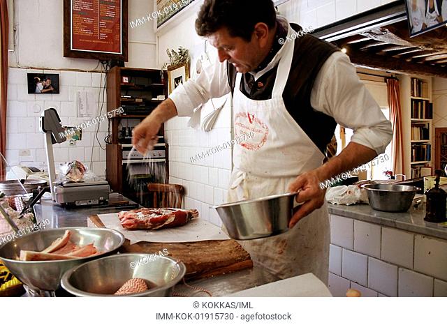 Traditional butcher's shop, man putting salt on meat , Panzano, Tuscany, Italy, Europe