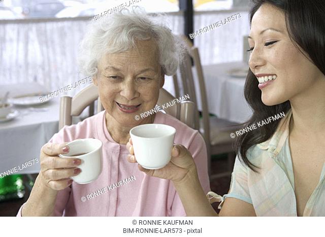 Mother and grown daughter toasting with tea
