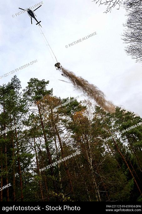 25 November 2022, Lower Saxony, Unterlüß: A helicopter is used to spread magnesium lime over a forest area. In the Lüneburg Heath, a forest area of almost 1