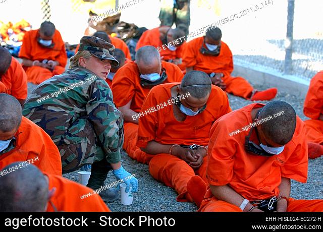 U.S. Military Police woman provides water to chained detainees as they arrive at Camp X-Ray at Guantanamo Bay Naval Base