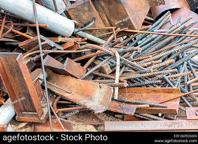 Pile of scrap metal with concrete steel and several pieces construction equipment