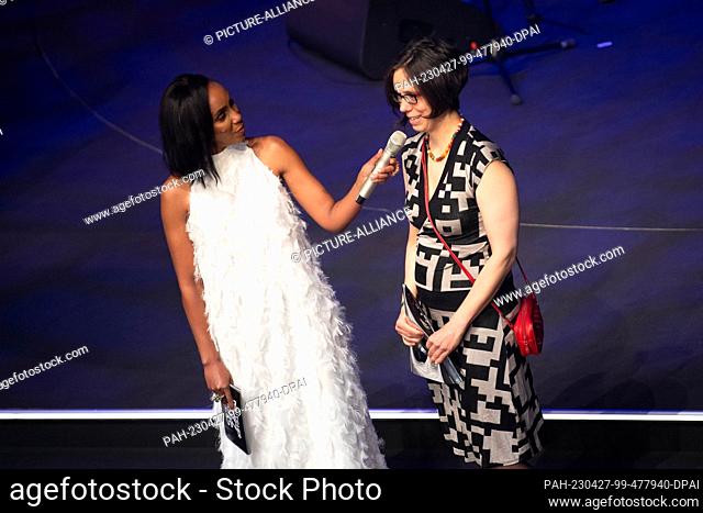 27 April 2023, Bremen: Almut Schlichtung (r) of the Insomnia Brass Band, winner of the award for best band of the year, stands on stage next to presenter Hadnet...