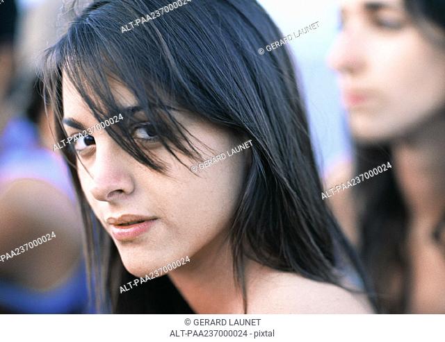 Young woman looking at camera, close-up portrait, friends in background