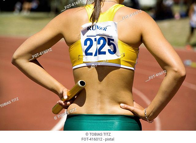 Female athlete holding a relay baton at the beginning of a race