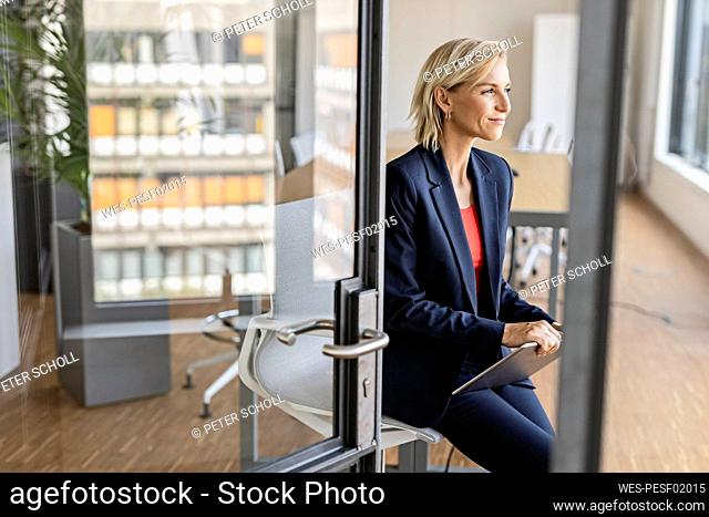 Blond businesswoman holding tablet in conference room