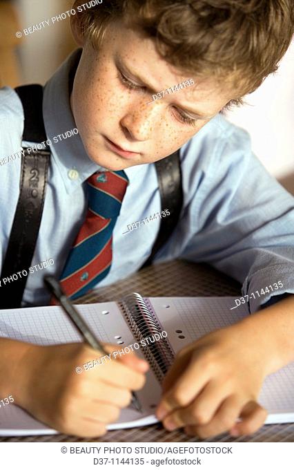 Caucasian boy writing on a notebook concentrated