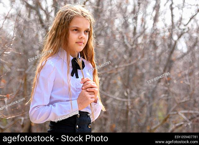 Portrait of a girl with dried wildflowers in her hands on a forest background
