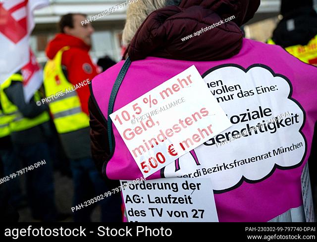 02 March 2023, Bavaria, Munich: A note with the inscription ""10.5% more money, at least ·500 more"" is seen on the vest of a woman during the rally of...