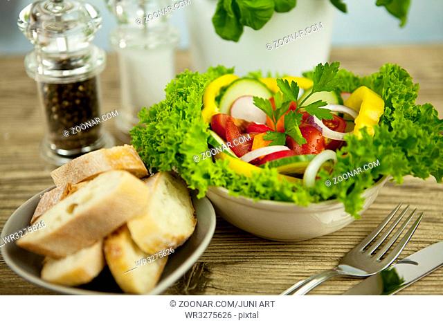 frischer gesunder gemischter salat mit brot auf einem Holzbrett