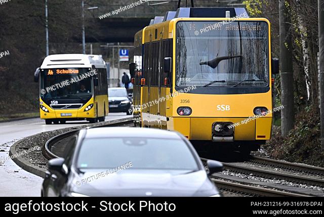 PRODUCTION - 15 December 2023, Baden-Württemberg, Stuttgart: A streetcar runs in Stuttgart-Vaihingen next to a road on which cars and a bus drive