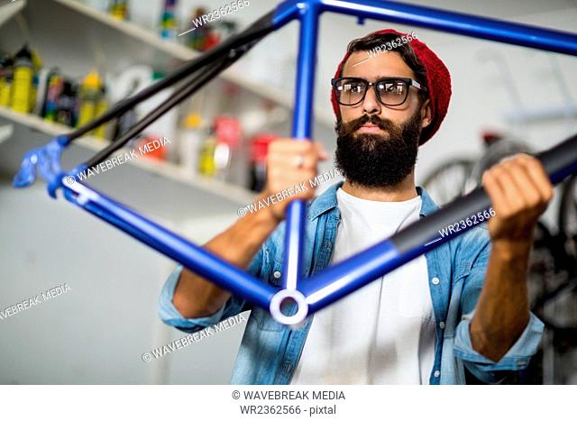 Hipster bike mechanic holding a bike piece