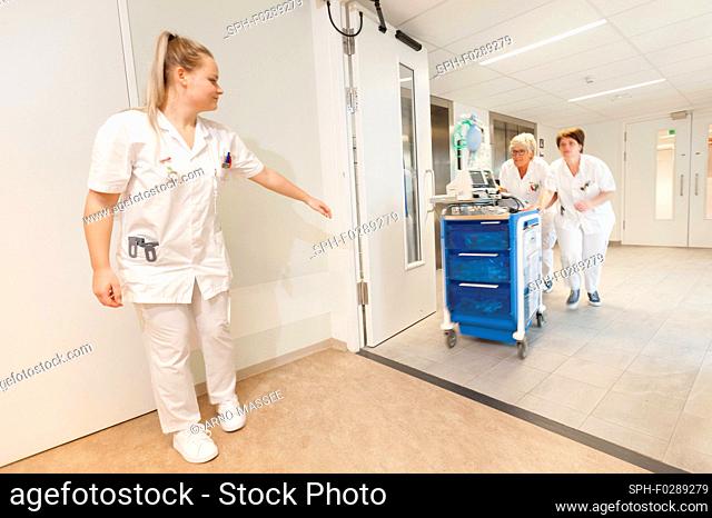 Geriatric hospital ward. Nurses running through the hall of a hospital geriatric ward with a trauma crash cart