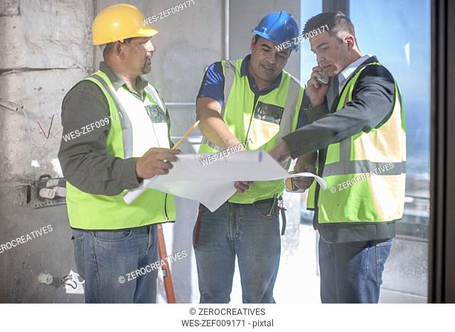 Architect and construction workers discussing construction plan