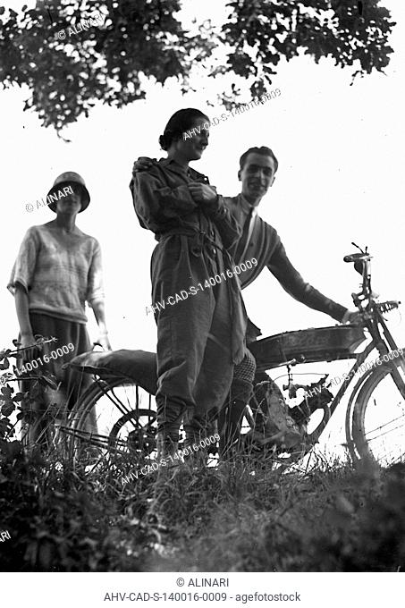 Group posing next to a motorcycle, Castelnuovo, shot 08-09/06/1924 by Monteverde, Aurelio
