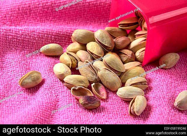 Pistachios in container on pink background