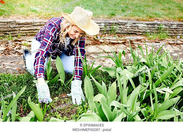 Young woman with a straw hat weeding weeds