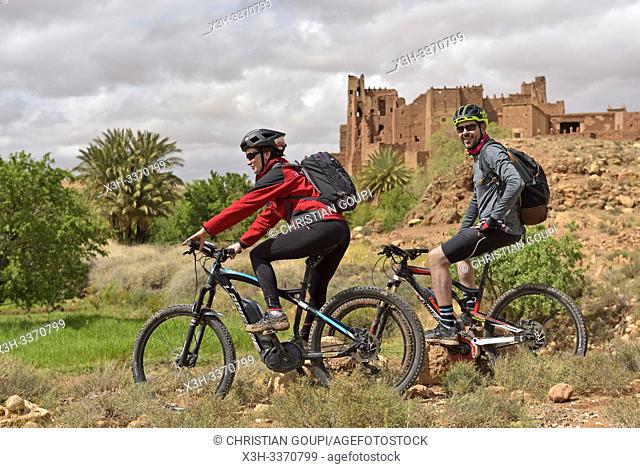 riders on mountain bike with electric assistance in front of the Ksar of Tamedakhte, Ounila River valley, Ouarzazate Province, region of Draa-Tafilalet, Morocco