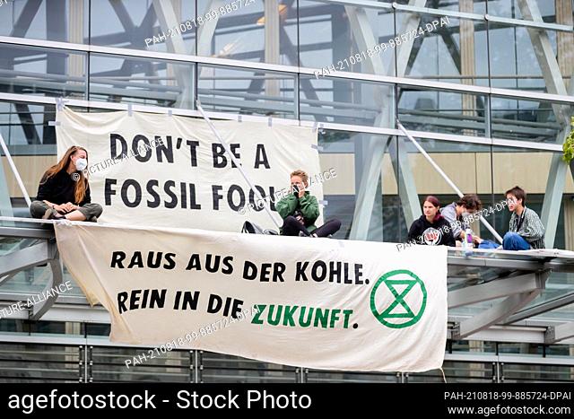18 August 2021, Berlin: Environmental activists sit next to banners on a canopy during a blockade of the state representation of North Rhine-Westphalia (NRW)