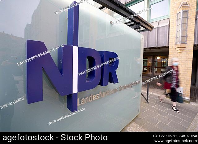 05 September 2022, Schleswig-Holstein, Kiel: A woman walks past a sign at the entrance to NDR's Schleswig-Holstein state broadcasting center