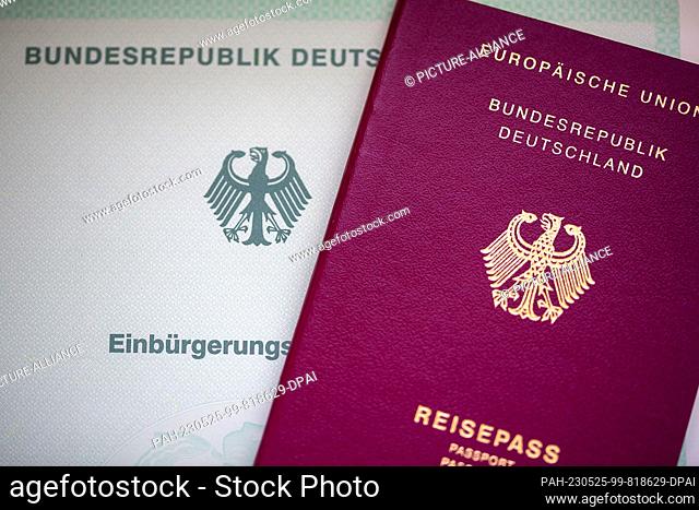SYMBOL - 22 May 2023, Berlin: A certificate of naturalization from the Federal Republic of Germany (l) and a German passport lie on a table