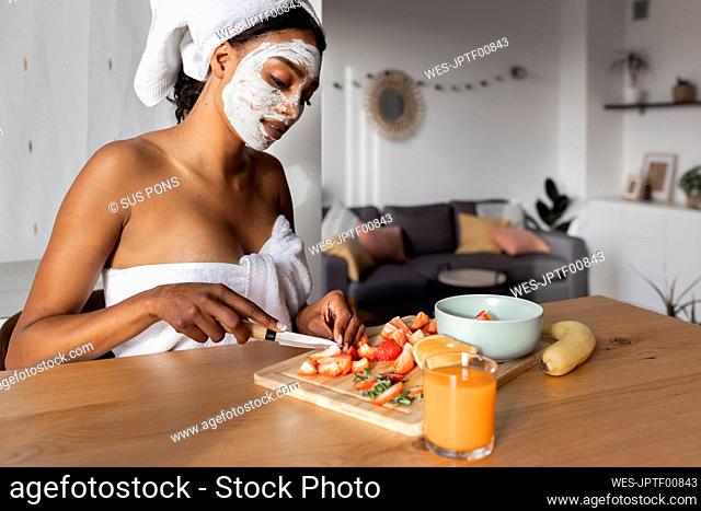 Young woman cutting fruits in kitchen at home