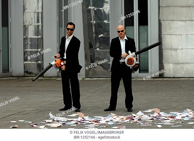Men in Black, two business people with leaf blowers and banknotes, symbolic of waste of money