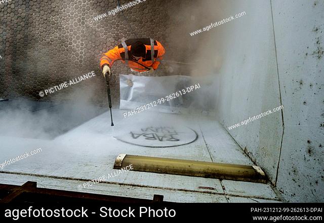 PRODUCTION - 05 December 2023, Hesse, Frankfurt/Main: Berthold Holterhöfer, cleaning specialist, removes graffiti at the entrance to the Niddapark subway...