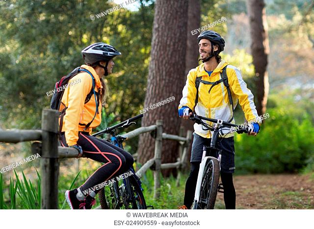 Biker couple interacting with each other in forest