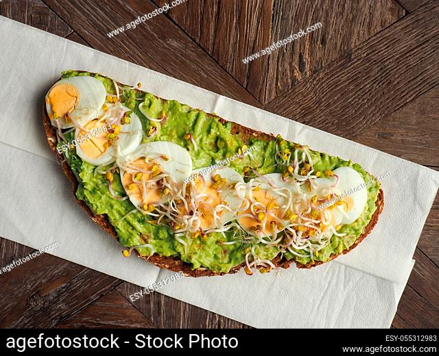 Tasty organic bread with Avocado cream and eggs on a rustic wooden table