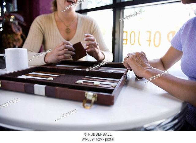 Mid section view of two women playing backgammon in a restaurant