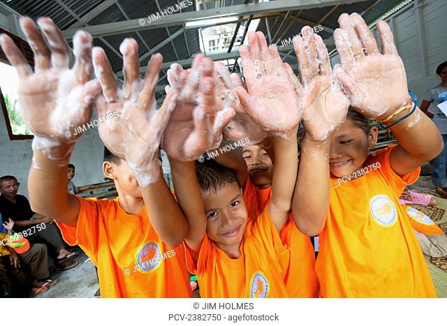 Children show their hands with soap bubbles during a WASH (Water and Sanitation, Health) training for school children on Nias Island; Meulaboh, Aceh Province