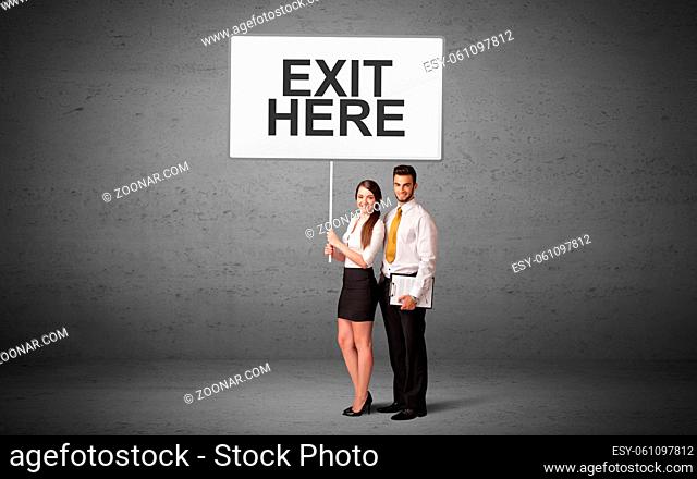 business person holding a traffic sign with EXIT HERE inscription, new idea concept