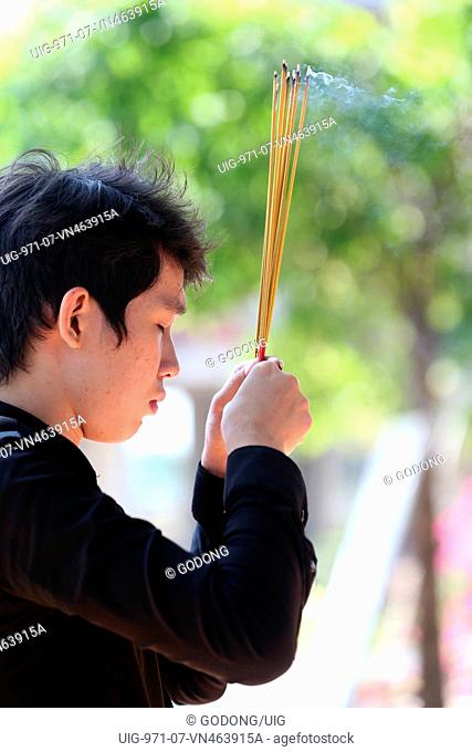 Chua Thien Lam Go buddhist pagoda. Man in prayer holding incense sticks