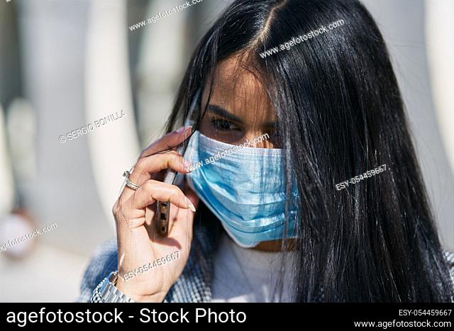 Girl with a mask to avoid contagion walking down the street. Coronavirus concept