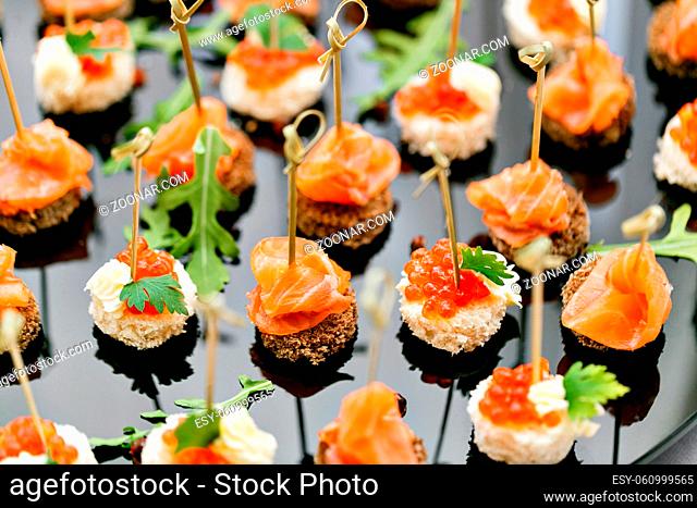 the buffet at the reception. Assortment of canapes. Banquet service. catering food, snacks with salmon and caviar. rye, wheat bread